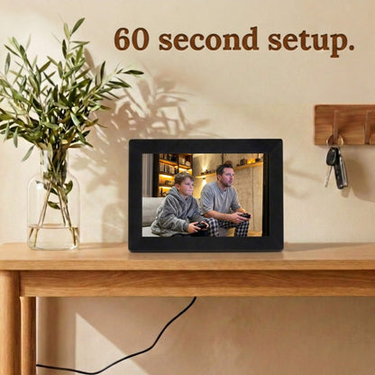 A 10-inch black Family Frame electronic photo frame displayed prominently on a light wooden console table in a bright room. Prioritizing accessibility, this intuitive smart picture frame boasts a frictionless, easy 60-second WiFi setup process that anyone can master in minutes. This completely no subscription fee digital frame ensures immediate and uninterrupted photo sharing for families of all technical backgrounds.

