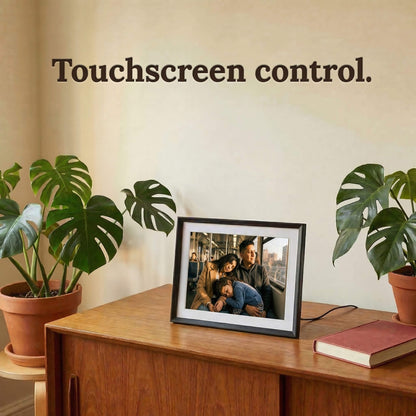 A 10-inch classic black Family Frame photo sharing frame featuring a classic white mat, resting on a vintage mid-century modern cabinet. This high-end WiFi photo frame provides an effortless user experience through a highly responsive, intuitive touchscreen control interface. Recognized as an ideal long-distance family gift, it offers unlimited users the ability to send and curate daily photo updates completely free of subscription charges.
