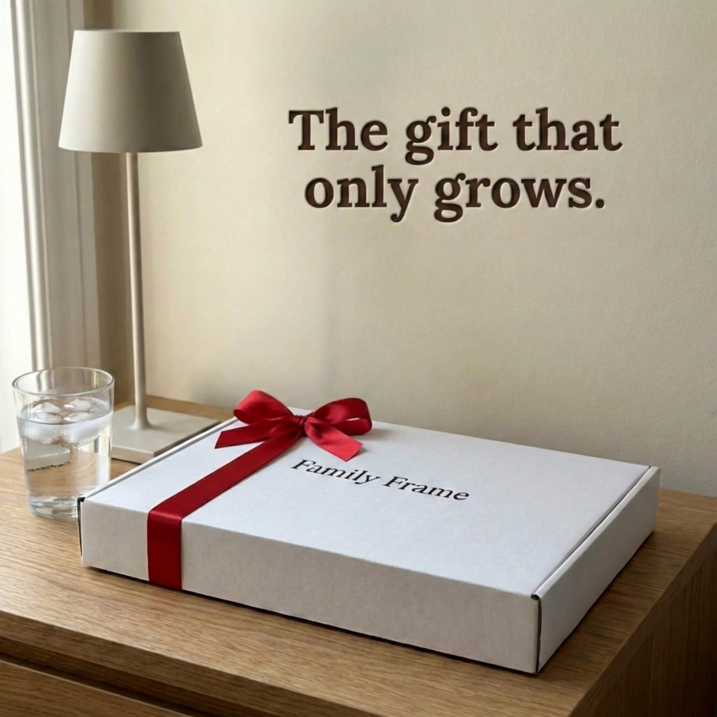 A 10-inch cordless classic black Family Frame smart picture frame packaged elegantly in a white gift box with a red bow, sitting on a bedside table beside a reading lamp. Perfectly presented as a luxury long-distance family gift, this beautifully boxed cordless WiFi photo frame is built to foster daily emotional connections. The premium electronic photo frame serves as a continuous digital memory display, updating effortlessly through its dedicated secure application.
