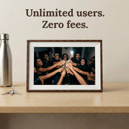 A 10-inch cordless mocha wood Family Frame digital picture frame with a clean white mat placed on a bright desk beside a silver water bottle. Built to gather the whole family, this battery-operated smart picture frame securely accepts photo uploads from an unlimited number of invited users around the globe. Operating entirely as a no subscription fee digital frame, it represents the most cost-effective way to maintain long-distance family connections over time.

