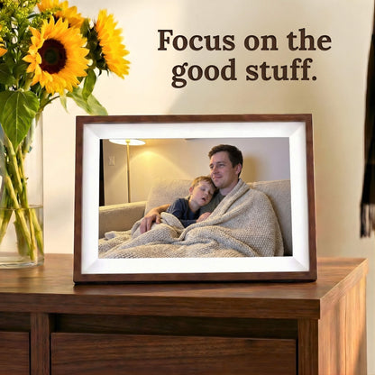 A 10-inch cordless mocha wood Family Frame smart picture frame featuring a pristine white mat, situated on a dark wooden dresser. Designed for vivid visual storytelling, this cordless WiFi photo frame delivers a stunning high-resolution display that beautifully highlights the details of every uploaded image. Acting as a dedicated digital memory display, the battery-operated device bridges the physical distance between family members with a constant stream of new photos.
