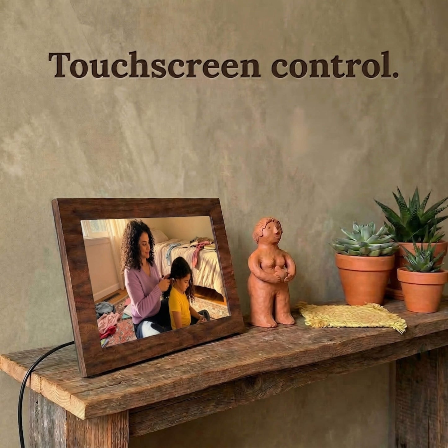A 10-inch oak wood Family Frame photo sharing frame resting on a weathered rustic table surrounded by small succulent plants. This high-end WiFi photo frame provides an effortless user experience through a highly responsive, intuitive touchscreen control interface. Recognized as an ideal long-distance family gift, it offers unlimited users the ability to curate daily photo updates completely free of subscription charges.