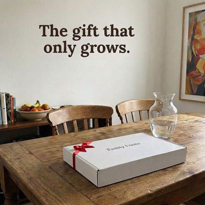 A 10-inch oak wood Family Frame smart picture frame packaged elegantly in a premium white gift box with a red bow, sitting on a solid wood dining table. Perfectly presented as a luxury long-distance family gift, this beautifully boxed WiFi photo frame is built to foster daily emotional connections. The premium electronic photo frame serves as a continuous digital memory display, updating effortlessly through its dedicated secure application.
