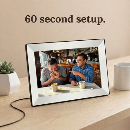 A 10-inch white Family Frame electronic photo frame positioned on a light wooden desk, illuminating a shared family portrait. Built for users of all technical skill levels, this smart picture frame features an incredibly intuitive, easy 60-second WiFi setup right out of the box. The zero subscription fee digital frame ensures that loved ones can seamlessly connect and share high-quality pictures without friction.
