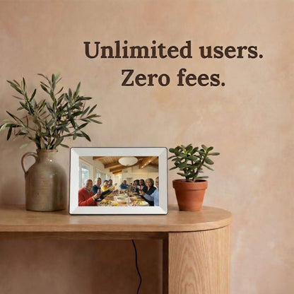 A 10-inch white Family Frame digital picture frame displayed on a hallway table surrounded by rustic ceramic vases. Designed to unite entire family networks, this smart picture frame supports an unlimited number of users securely uploading images from their smartphones. This completely no subscription fee digital frame guarantees a lifetime of free photo sharing and private connection for long-distance relatives.
