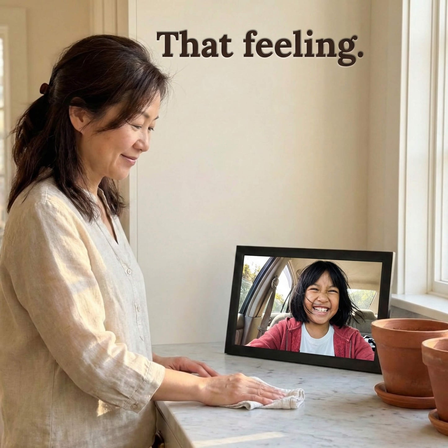 A 16-inch black Family Frame WiFi photo frame being viewed joyfully by a user wiping down her kitchen counter. Engineered specifically as a heartwarming long-distance family gift, this sleek smart picture frame instantly receives new photos from loved ones living far away. It functions as a powerful digital memory display to consistently spark joy and combat loneliness through effortless photo sharing.
