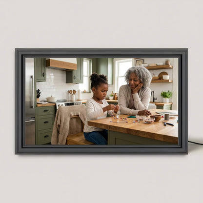 A 16-inch studio black Family Frame digital picture frame resting on a bright kitchen island, displaying a crisp family photo. This premium smart picture frame features an HD digital photo display designed to seamlessly blend into home decor while sharing everyday moments. Built as the ultimate long-distance family gift, this WiFi photo frame keeps loved ones connected with zero subscription fees.
