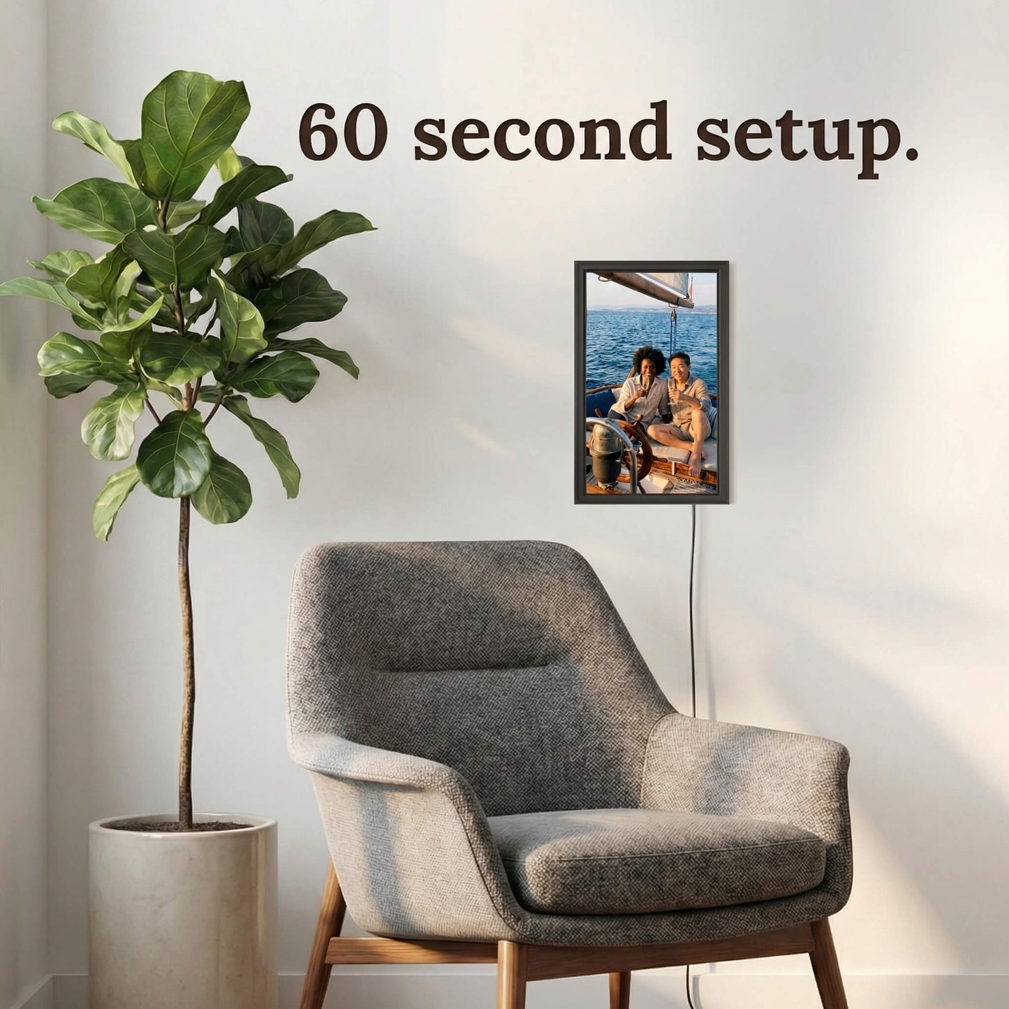 A 16-inch studio black Family Frame electronic photo frame mounted vertically on a wall next to a comfortable reading chair and an indoor plant. Designed for absolute ease of use, this smart picture frame features an incredibly simple, easy 60-second WiFi setup right out of the box. This completely no subscription fee digital frame ensures immediate and frictionless photo sharing for users of all technical backgrounds.
