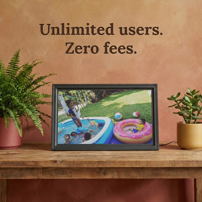 A 16-inch studio black Family Frame digital picture frame sitting on a rustic wooden table illuminated by warm natural light. Built to unite large families, this smart picture frame securely accepts instant uploads from an unlimited number of invited users globally. Operating entirely as a no subscription fee digital frame, it represents the most reliable way to maintain long-distance family connections over time.
