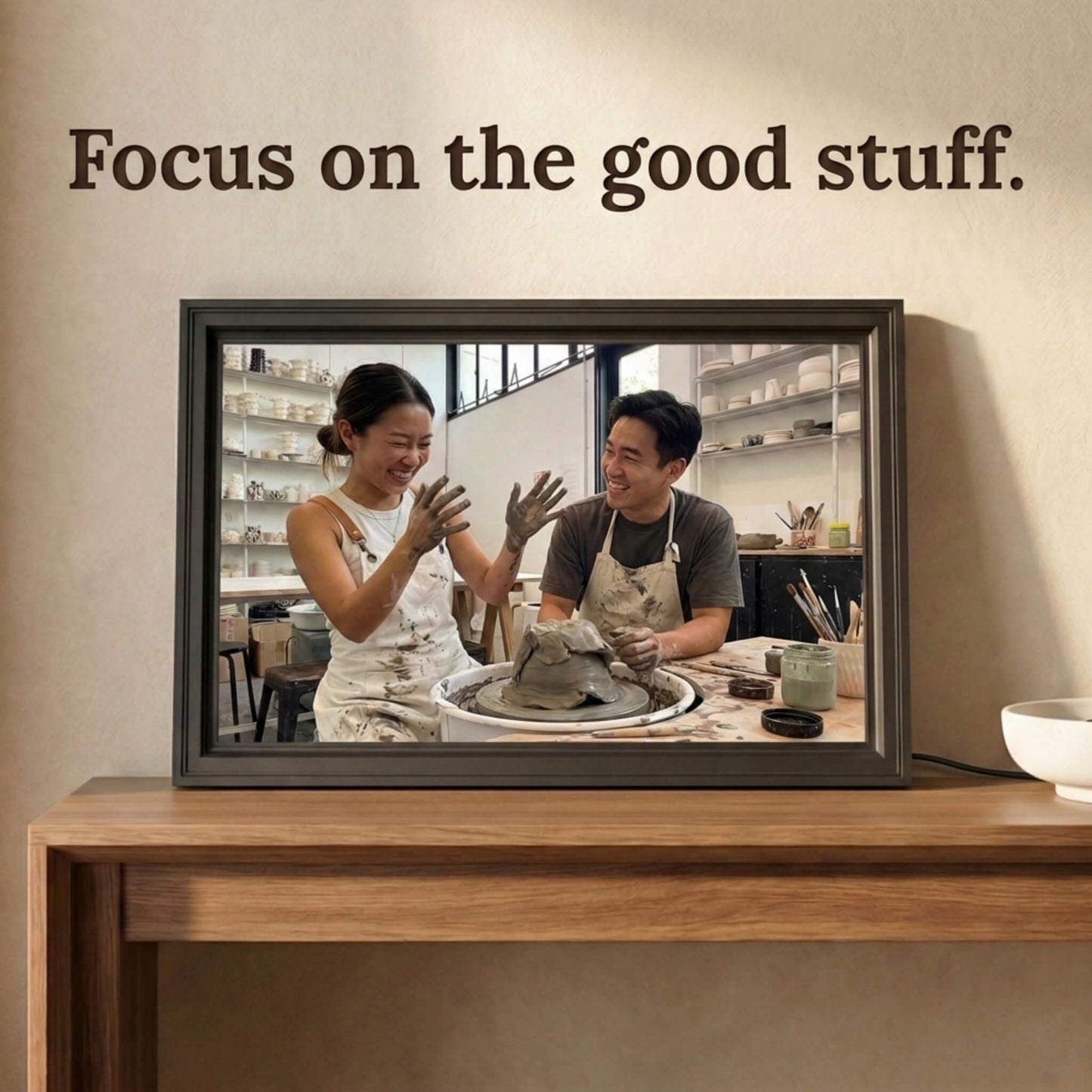 A 16-inch studio black Family Frame smart picture frame situated on a natural wood console table. Delivering a vibrant high-resolution display, this electronic photo frame showcases high-quality images with stunning, true-to-life clarity. Functioning as a dedicated digital memory display, it bridges physical distances between relatives through constant, beautiful photo updates.