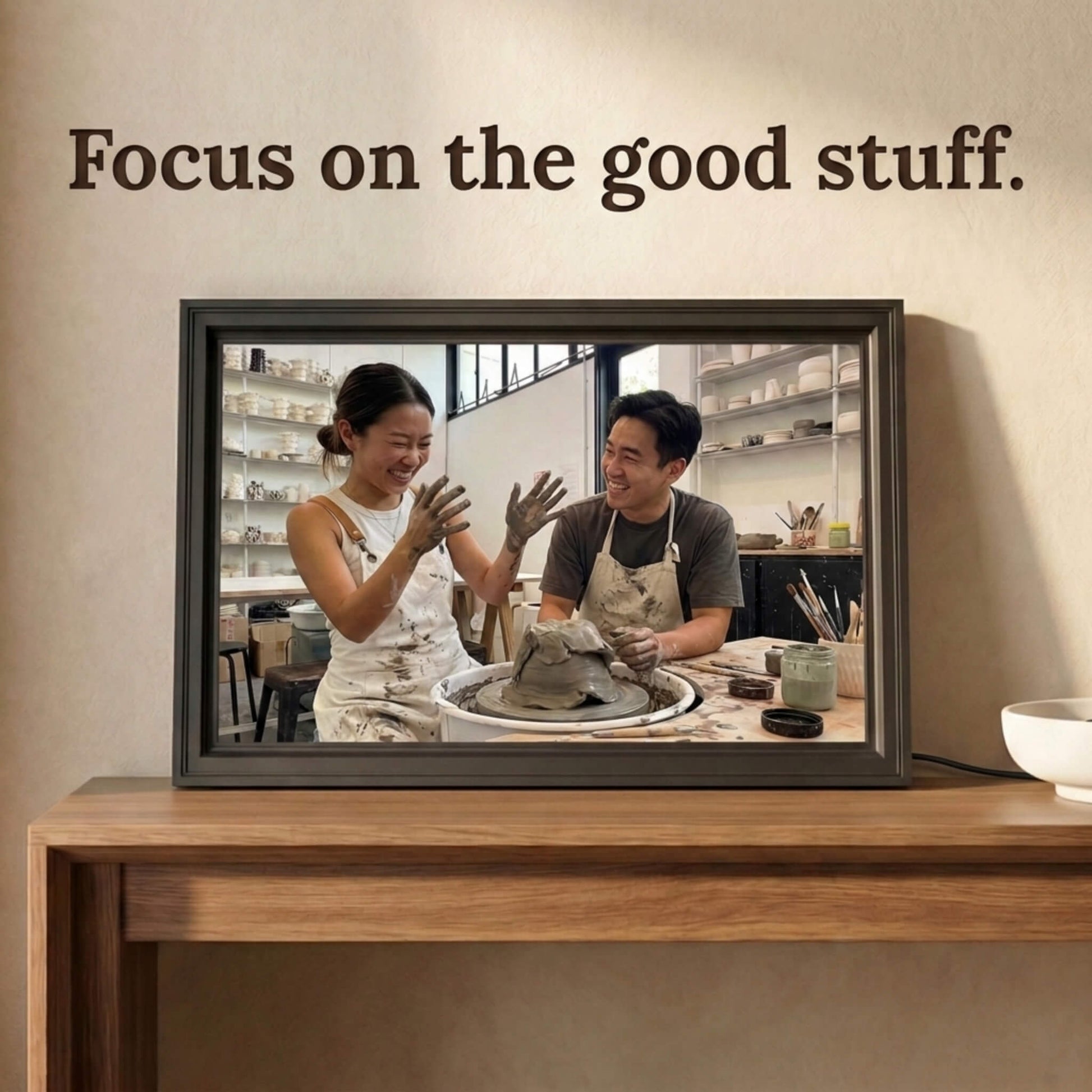 A 16-inch studio black Family Frame smart picture frame situated on a natural wood console table. Delivering a vibrant high-resolution display, this electronic photo frame showcases high-quality images with stunning, true-to-life clarity. Functioning as a dedicated digital memory display, it bridges physical distances between relatives through constant, beautiful photo updates.