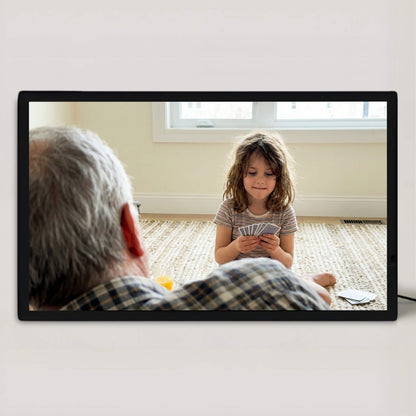 A 20-inch black Family Frame digital picture frame mounted cleanly on a white wall, showcasing a bright, full-bleed photograph without a mat. This oversized premium smart picture frame utilizes an HD digital photo display designed to transform cherished memories into striking wall art. Built as the ultimate long-distance family gift, this plug-in WiFi photo frame seamlessly connects loved ones across the country with zero subscription fees.
