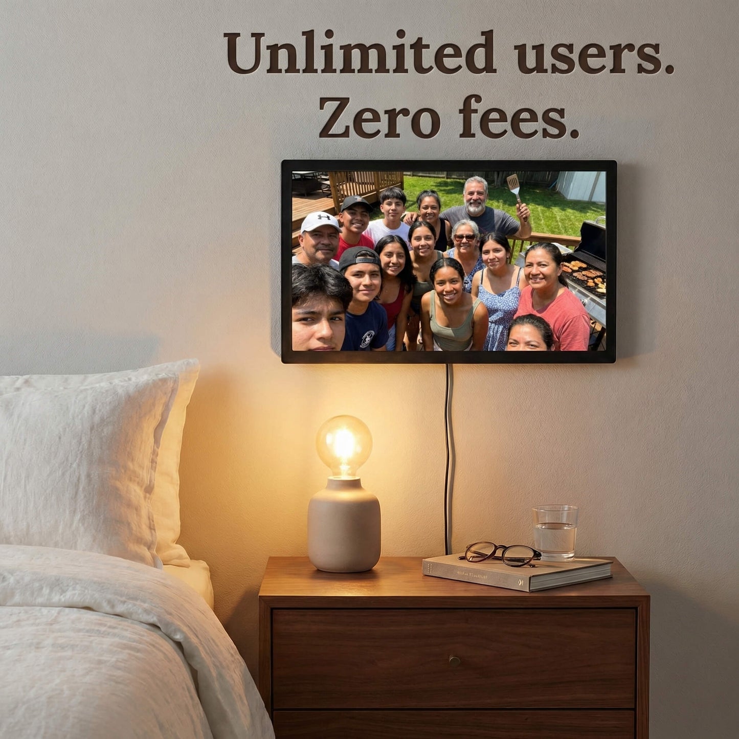 A 20-inch black Family Frame digital picture frame mounted on a bedroom wall directly above a glowing bedside lamp. Built to gather the whole family, this expansive smart picture frame securely accepts photo uploads from an unlimited number of invited users around the globe. Operating entirely as a no subscription fee digital frame, it represents the most cost-effective way to maintain long-distance family connections over time.
