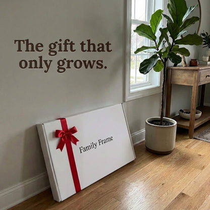 A 20-inch black Family Frame smart picture frame packaged elegantly in a massive white gift box with a red bow, leaning against a neutral wall beside a potted ficus. Perfectly presented as a luxury long-distance family gift, this beautifully boxed WiFi photo frame is built to foster daily emotional connections. The premium electronic photo frame serves as a continuous digital memory display, updating effortlessly through its dedicated secure application.