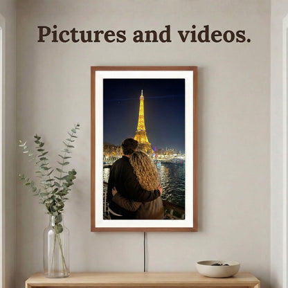 A vertically mounted 20-inch oak wood Family Frame digital memory display with an elegant white mat positioned above a light wood console table. Equipped with advanced processing, this premium digital picture frame flawlessly handles both high-definition photo and video playback to capture full, immersive memories. The robust photo sharing frame allows distant relatives to securely send video messages directly to the living room display.
